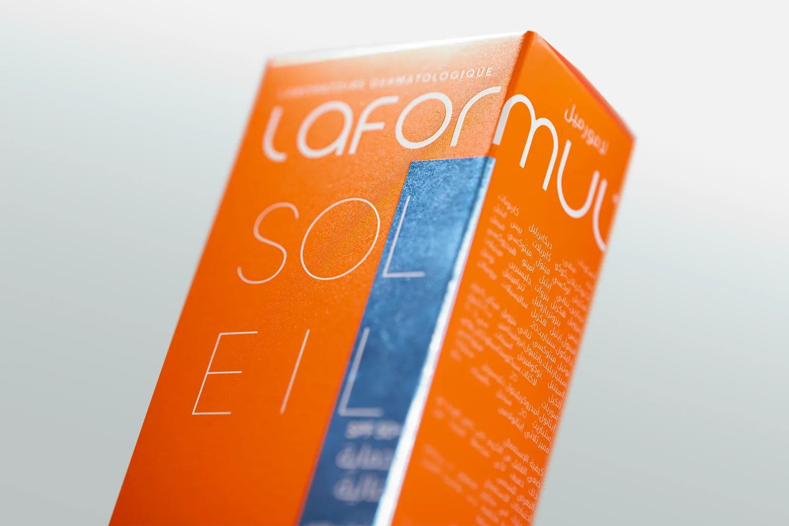 The Laformul Soleil carton, close up: the wordmark reversed out of orange beside a reflective blue band