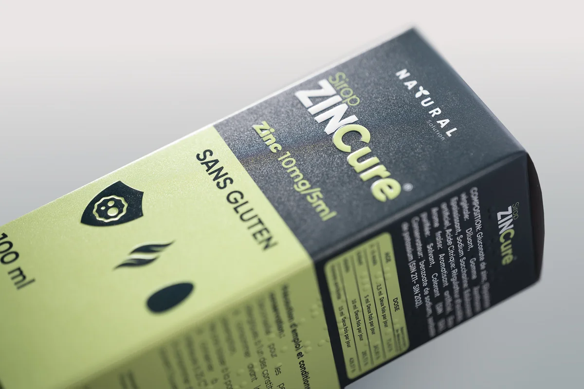 The Sirop ZINCure carton, close up: the name and icons embossed, braille along the side panel